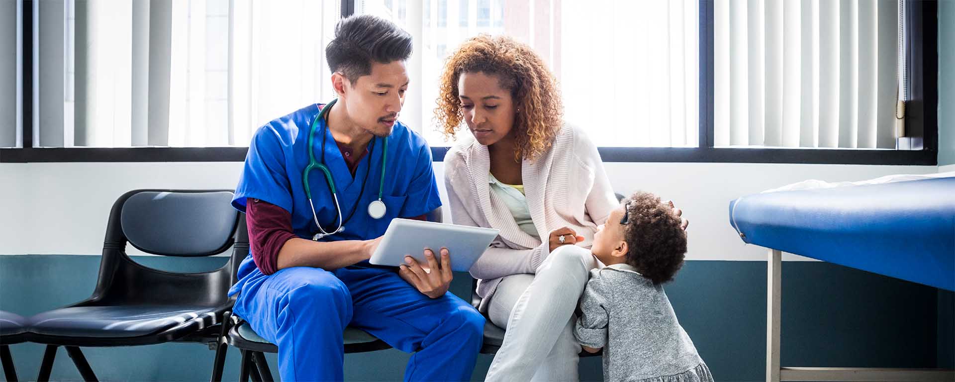 Healthcare worker showing tablet to patient and child