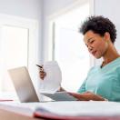 Healthcare worker looking at papers at a desk with a laptop