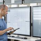 Healthcare worker with tablet looking at data displays