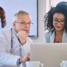 Doctor and businessperson looking at laptop screen