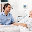 A nurse sitting beside a patient in bed