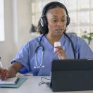 Doctor talking notes while talking to a tablet