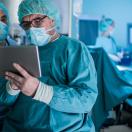 Surgeons looking at a tablet with operating room in background