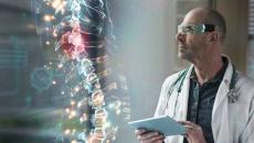 Healthcare worker with tablet looking at a digital display of a human spine