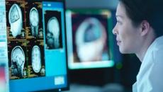 Healthcare worker looking at brain imaging on monitor