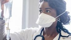 Healthcare worker in mask holding IV drip bag