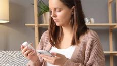 Person holding pill bottle and smart phone