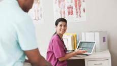 Healthcare worker with laptop talking to patient