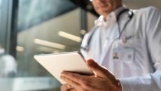 A doctor reading a medical chart from a tablet computer