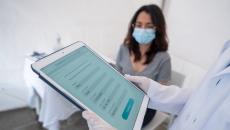 Healthcare provider on a tablet with a patient sitting in a room