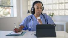 Doctor talking notes while talking to a tablet