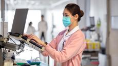 Healthcare worker in mask using laptop terminal