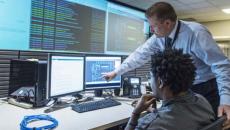 Two people examine screens with data displayed