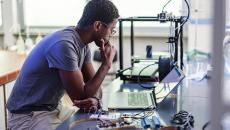 Worker looking at laptop surrounded by electronic components