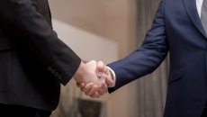 Two men in suits shake hands 