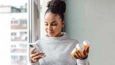 Person holding pill bottles and phone