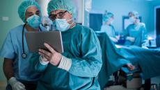 Surgeons looking at a tablet with operating room in background