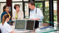 Doctor talking to mother and daughter at reception desk