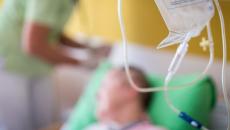 Infusion bag in foreground with patient and infusion nurse in background