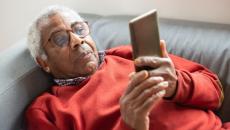 Person lies on couch reading from mobile phone 