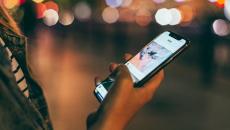 A person holding a phone by a street.