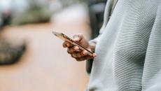 person in grey sweater using a mobile phone