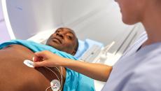 Technician puts ECG stickers on the chest of a man about to enter an MRI machine 