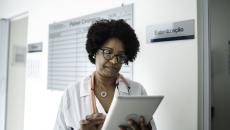 Female doctor reviews information on a tablet in a hallway