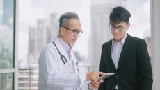 A doctor speaking with a person in a suit.