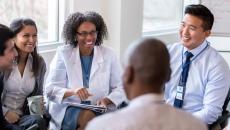 Hospital workers sit around in a meeting