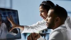 Two professionals examine computer screen