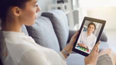 Person sits on couch while having a video visit with a mental health clinician