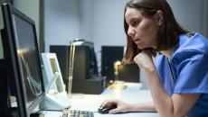 A doctor checking on a patient's file on a desktop computer