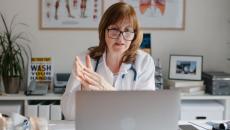 A doctor conducting an online consult in an office using a laptop