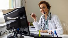 A doctor in a remote call using a desktop computer