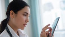 A doctor using a digital tablet to review a patient's file