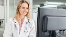 Doctor looks at a desktop computer screen in a medical office