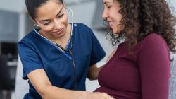 Doctor examining pregnant person with stethoscope