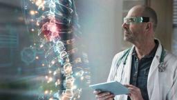 Healthcare worker with tablet looking at a digital display of a human spine