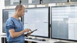 Healthcare worker with tablet looking at data displays