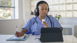 Doctor talking notes while talking to a tablet