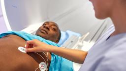 Technician puts ECG stickers on the chest of personabout to enter an MRI machine