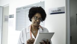 Female doctor reviews information on a tablet in a hallway