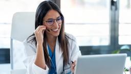 Female doctor with headset smiles on a telehealth visit