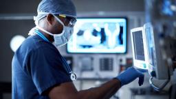 Healthcare worker in mask looking at display