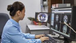 Woman reviews medical imaging on a desktop computer