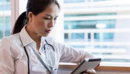 A doctor checking a patient's record on a digital tablet