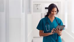 A doctor in scrubs reviewing a patient's record on a digital tablet