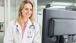 Doctor looks at a desktop computer screen in a medical office