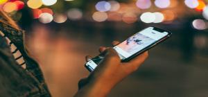 A person holding a phone by a street.